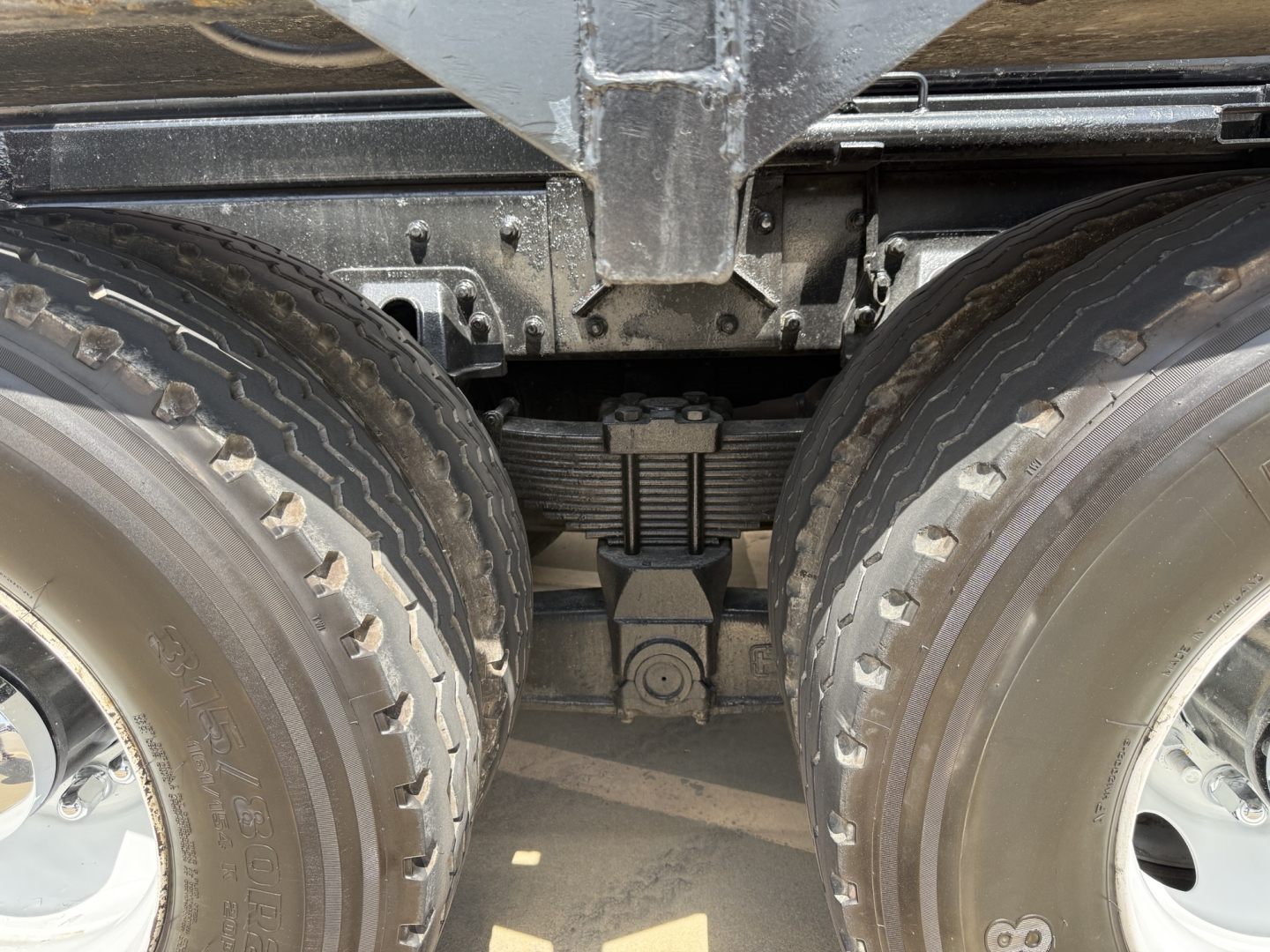 Kenworth T880 wheel area showing tandem axles and leaf spring suspension with differential housing visible between tires.