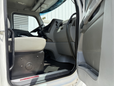 Kenworth T880 cab interior view from driver door opening showing steering wheel, dashboard, and seat.