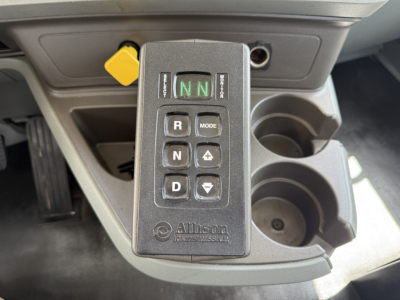 Kenworth T880 gear selector in cockpit showing N N with R, D, N, mode buttons; cup holders and yellow latch visible.
