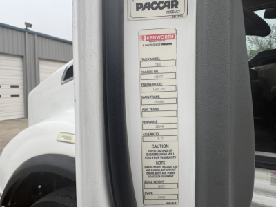 Kenworth truck serial label with PacCAR sticker and Kenworth branding on door jamb of 2018 Kenworth T880 roll-off truck showing engine model, chassis number, and warning text.