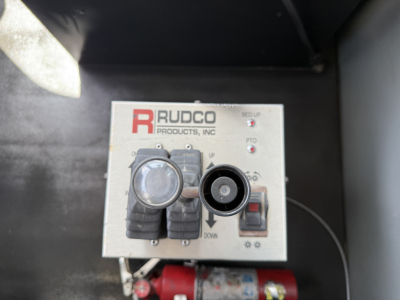 Kenworth T880 truck engine bay with Rudco control panel showing circular gauges and a red valve along with wiring harness.
