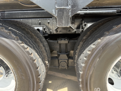 Kenworth T880 wheel area showing tandem axles and leaf spring suspension with differential housing visible between tires.