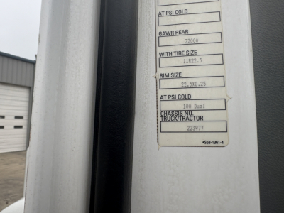 Label panel on Kenworth truck showing tire size and chassis data. Text includes 'GAWR REAR 22000', 'RIM SIZE 22.5J 8.25', 'WITH TIRE SIZE 11R22.5', 'CHASSIS NO. 223977' and other small lines.