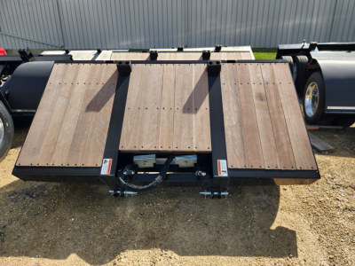 Trailer accessory showing flat wooden deck with metal frame and hitch components, branding labels, and hydraulic hose assembly in the center.