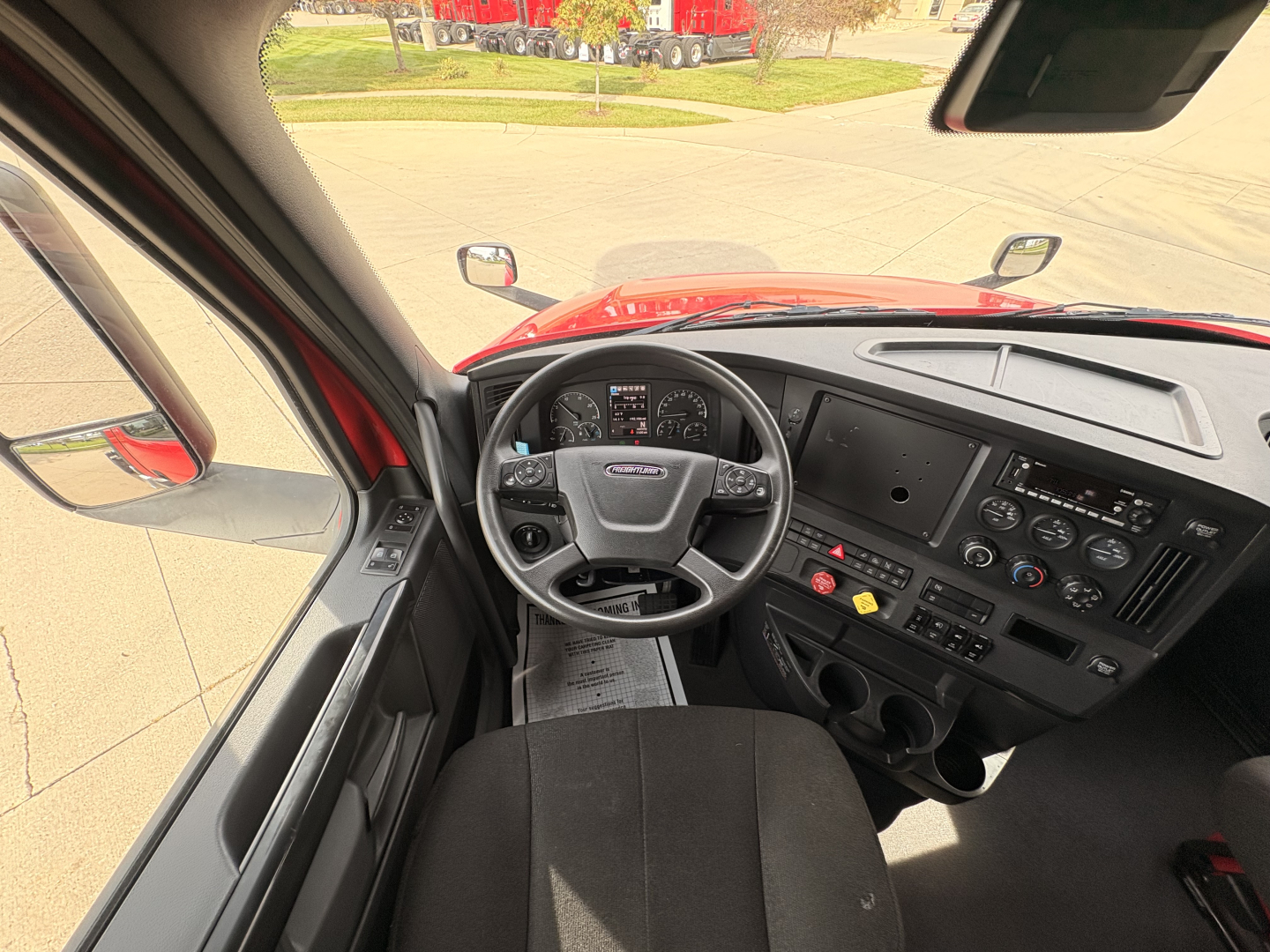 Interior view of a Freightliner PT126064S Daycab truck cabin showing steering wheel dashboard controls and center console.