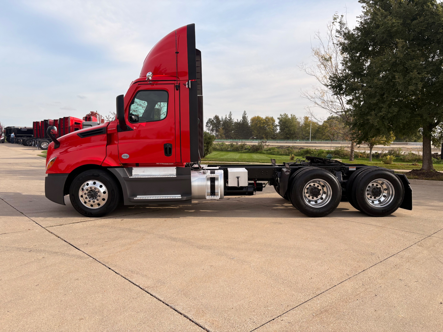 Truck chassis side view showing cab and 6x4 rear axle configuration with red cab and black frame.
