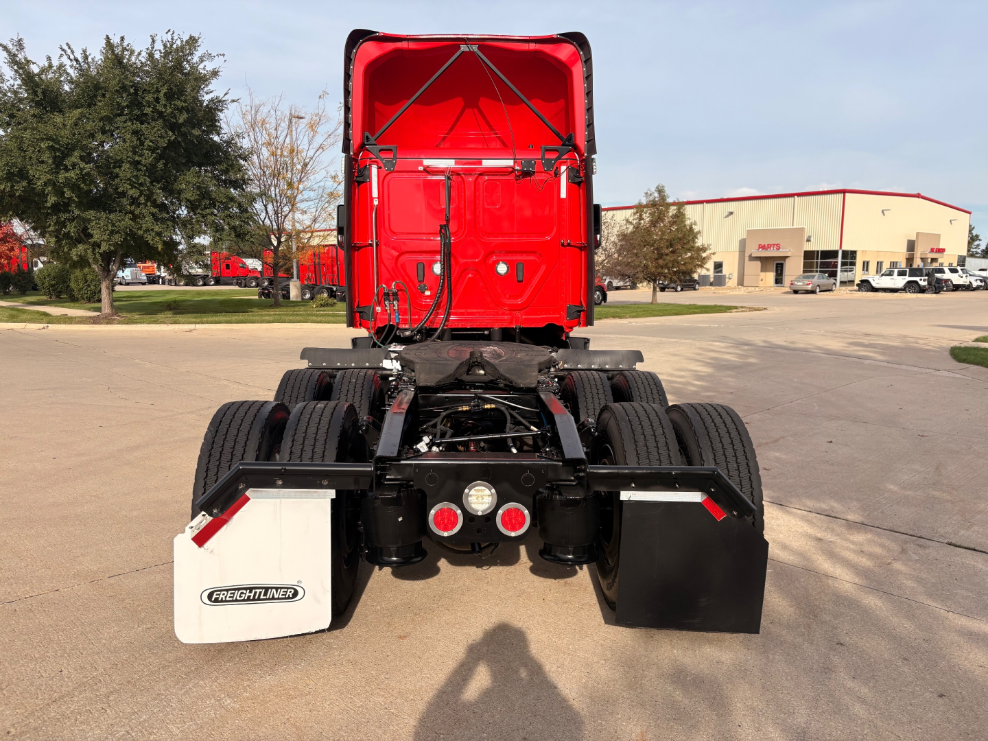 Rear view of a red Freightliner PT126064S T daycab truck showing rear bumper and fifth wheel area with mud flaps and company fittings.