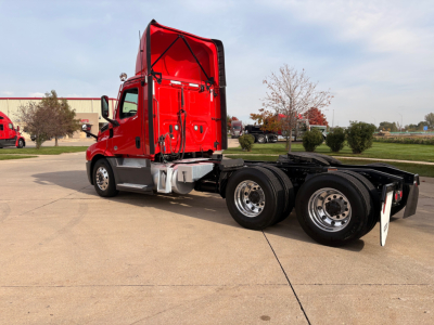 Freightliner PT126064S daycab tractor: red cab with raised sleeper, two rear axles, chrome fuel tanks, and fifth wheel visible.
