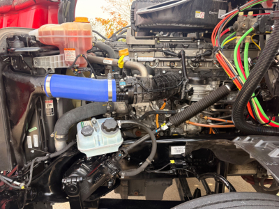 Freightliner PT126064S engine bay showing blue intercooler pipe, coolant reservoir, multiple hoses and wiring harnesses.