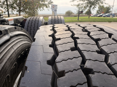 Conventional daycab tractor rear tires and dual axles showing tread pattern and wheel hubs.