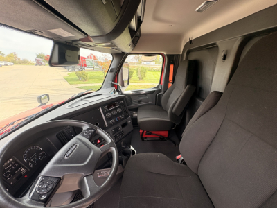 Truck cab interior showing steering wheel, dashboard, and passenger seat in a Freightliner day cab.