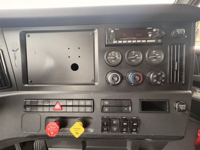 Cab interior of a Freightliner truck showing dashboard gauges, radio, control switches, and red and yellow handles; appears to be a daycab configuration.