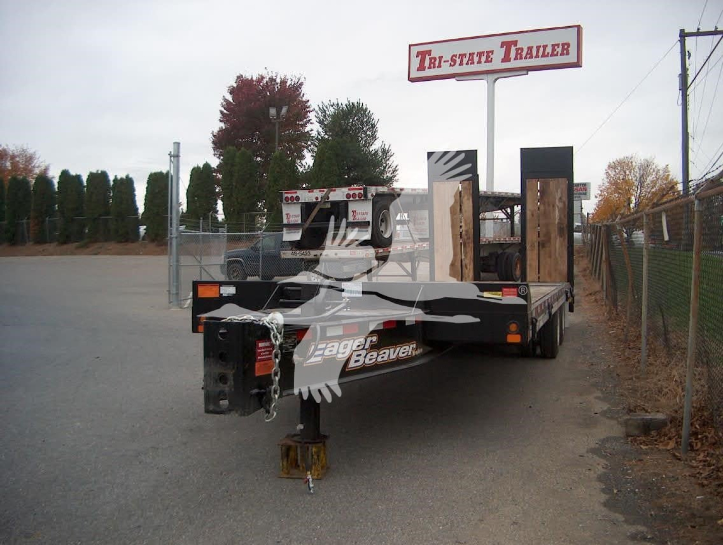 Trailer hitch area of a new 2026 Eager Beaver 20Xpt trailer showing front decking and safety chains.
