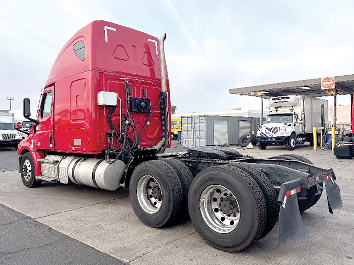2021 Freightliner Cascadia126 tractor cab with sleeper, red glossy exterior, showing rear dual-axle configuration and fifth wheel area.