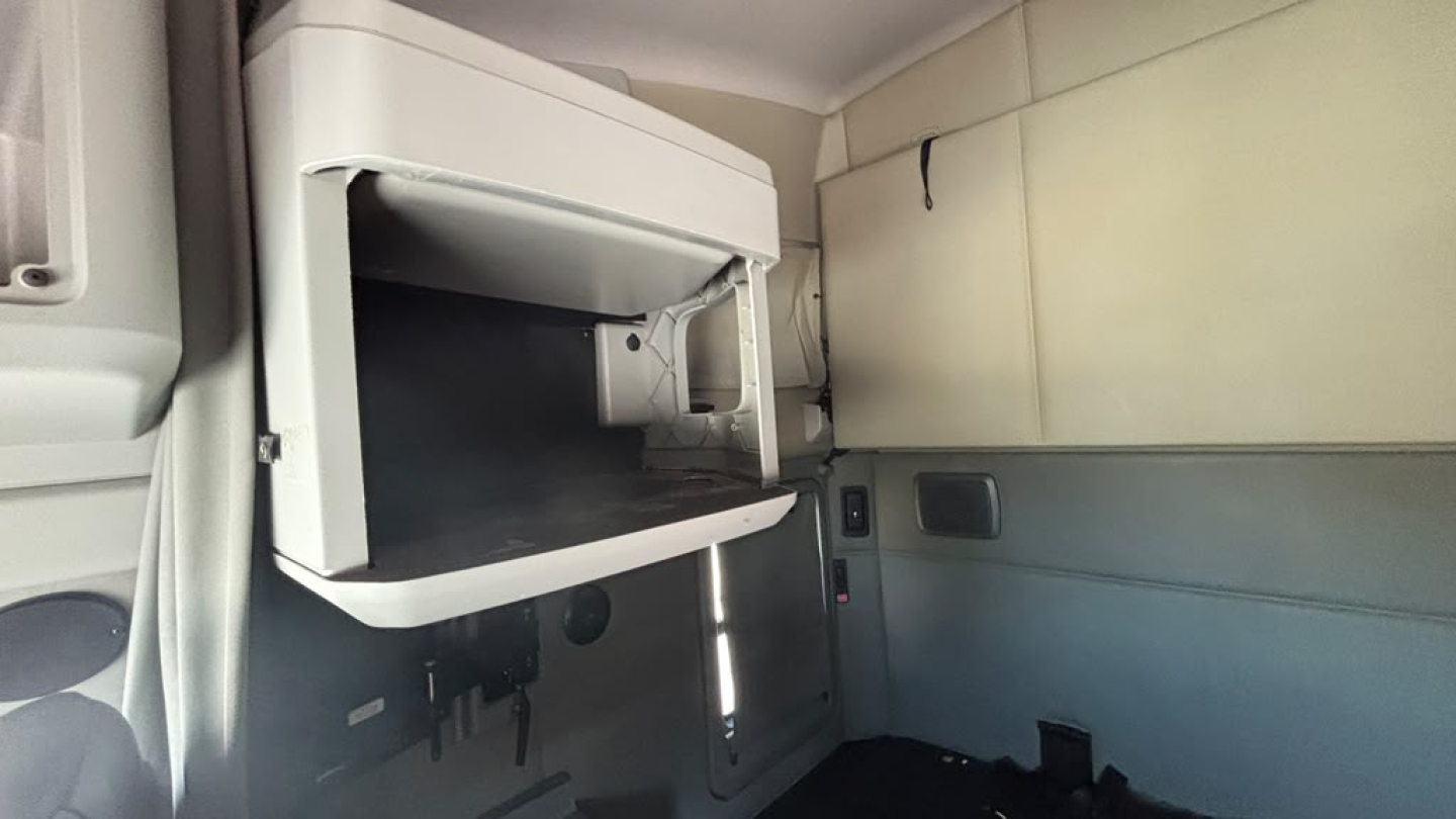 Kenworth T680 cab interior showing a fold-out bunk or shelf area with a mounted compartment and light gray walls.