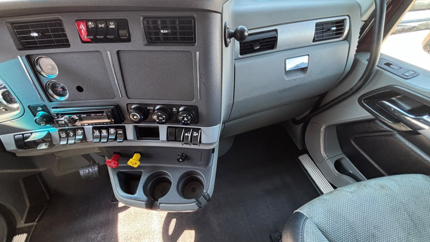 Kenworth T680 dashboard and center console view showing gauge cluster, controls, and cup holders.