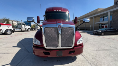 Kenworth T680 front view showing large chrome grille and headlights with burgundy paint and side mirrors.