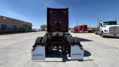 Kenworth T680 rear view showing trailer hitch area, two white mud flaps with MHC logos, and rear lights.