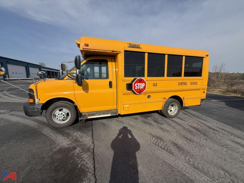 School bus side view showing yellow 2014 Chevrolet Express G3500 with stop sign, school district markings, and black tinted windows