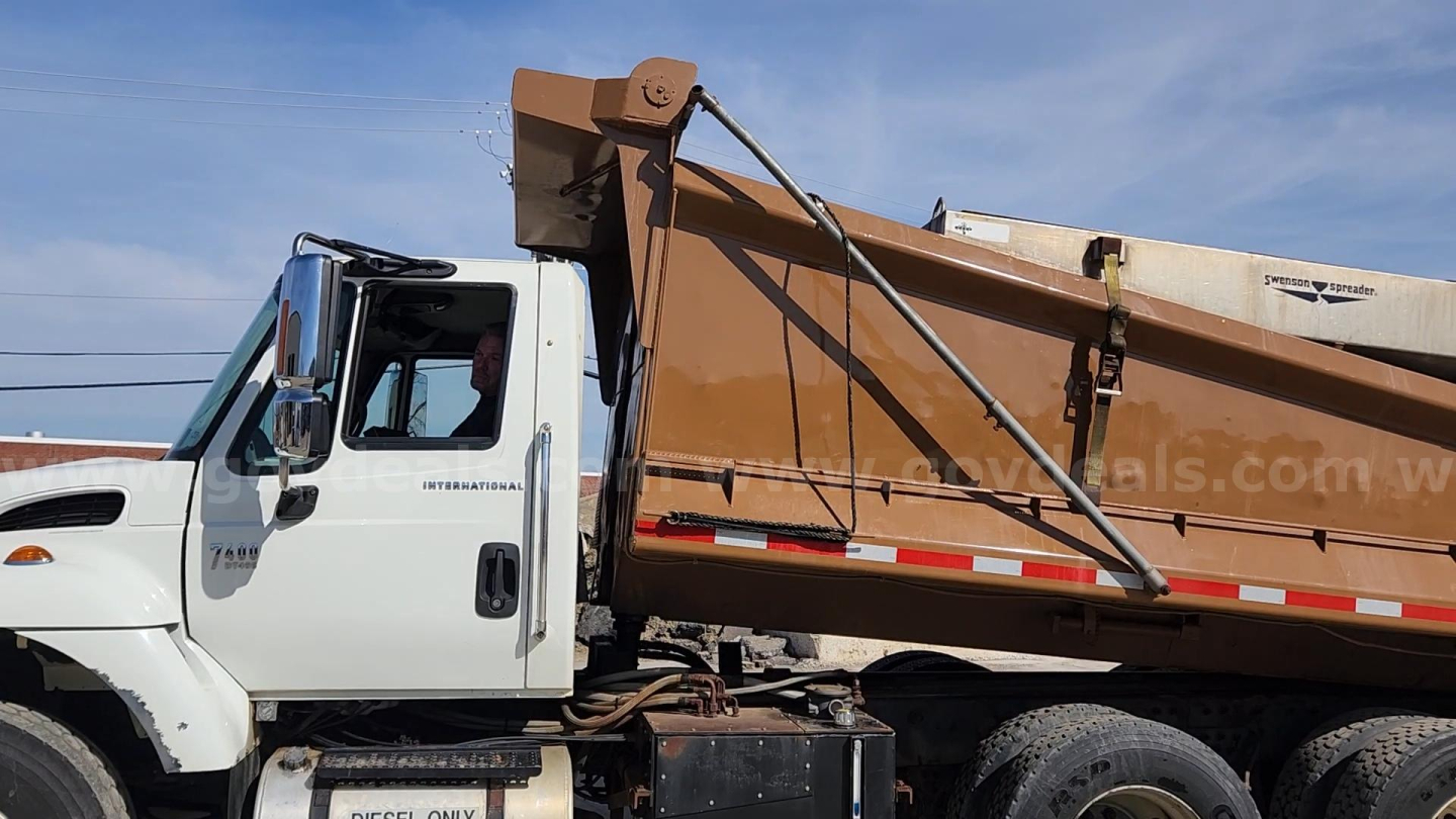 International 7400 dump truck side view showing hydraulic dump bed and white cab.