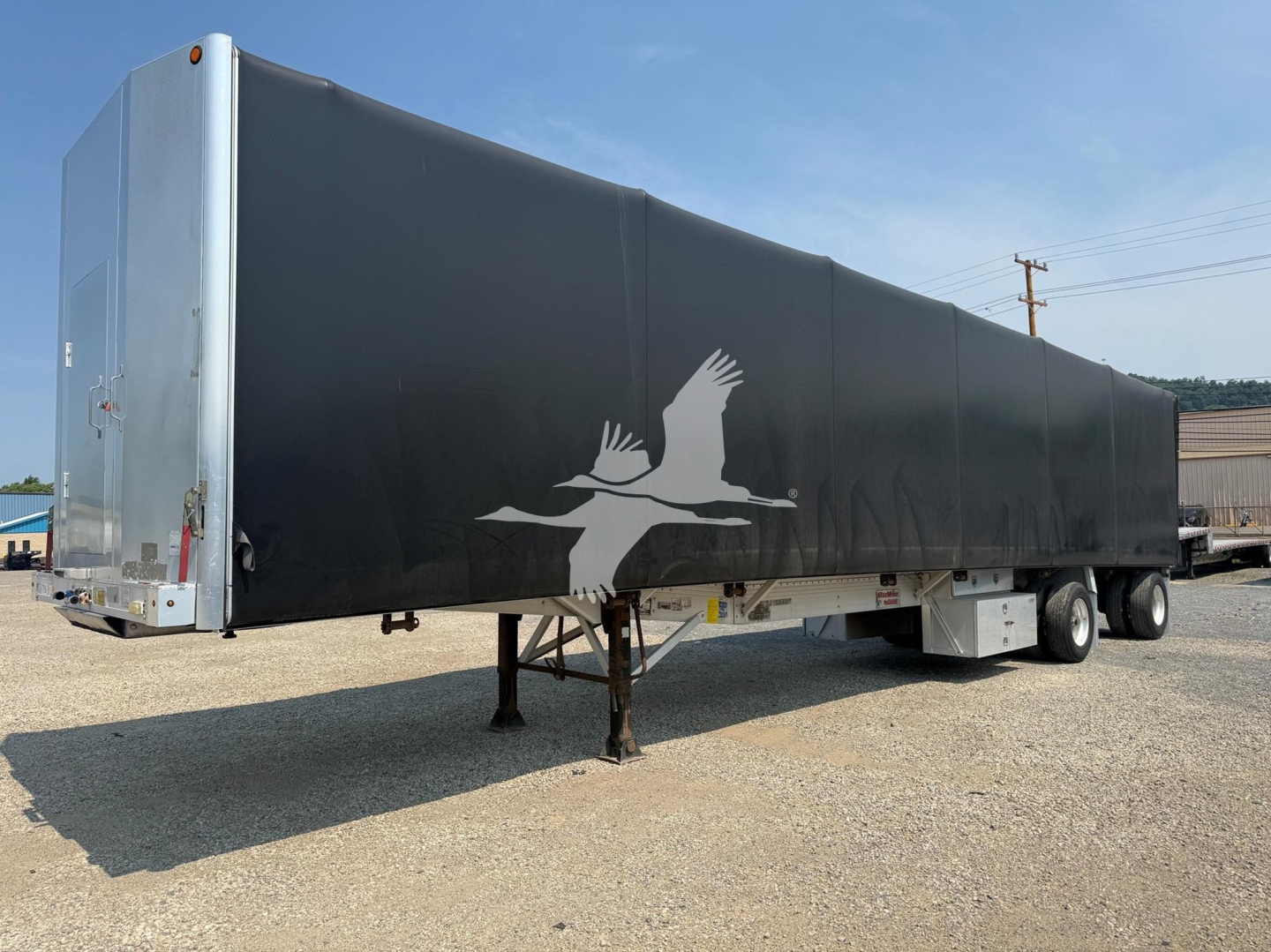 Trailer side view showing a 2012 Reitnouer Maxmiser curtainside trailer with black tarp, front-right dual wheels, and a white aerial bird logo. VIN 1RNF48A2XCR025613.