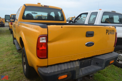 Ford F-250 Super Duty rear three-quarter view showing yellow pickup with tailgate, PU400 sticker, and 'SUPER DUTY' embossed on tailgate.