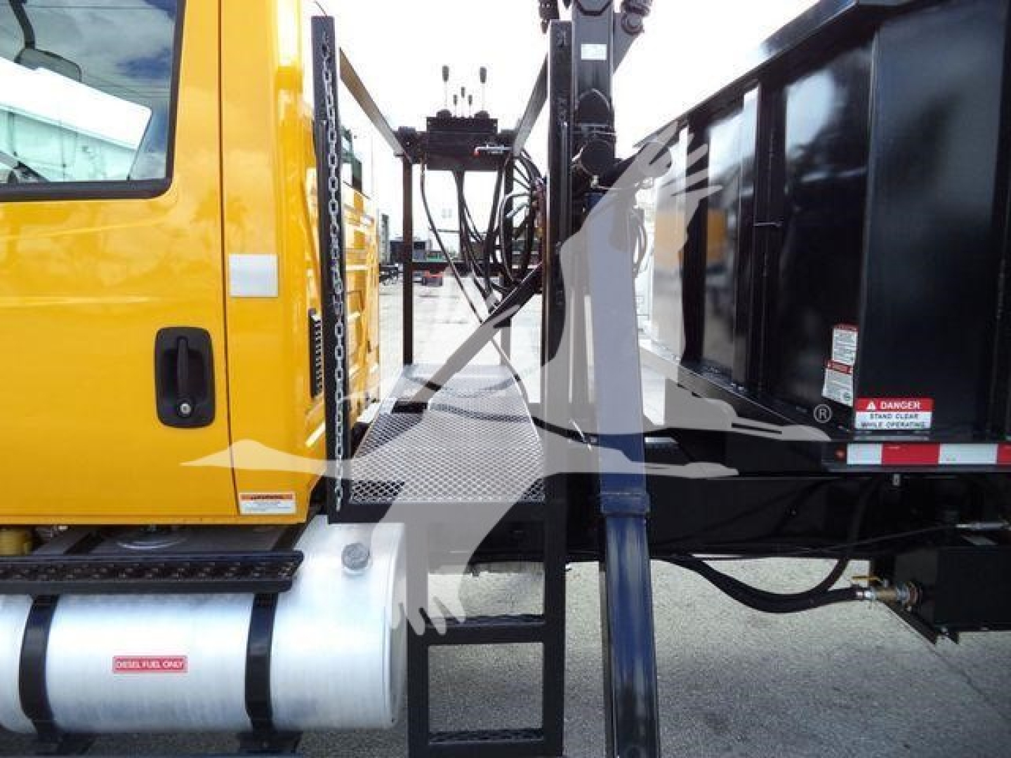 Side-view of a yellow International Durastar 4300 truck with a grapple attachment; visible text includes VIN block on windshield area and control panels; no legible serials visible on the image.