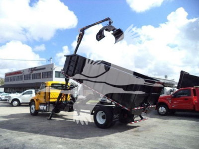 Grapple truck in service showing dump bed tilted up with hydraulic grapple arm extended, International Durastar 4300, stock and VIN visible in listing context.