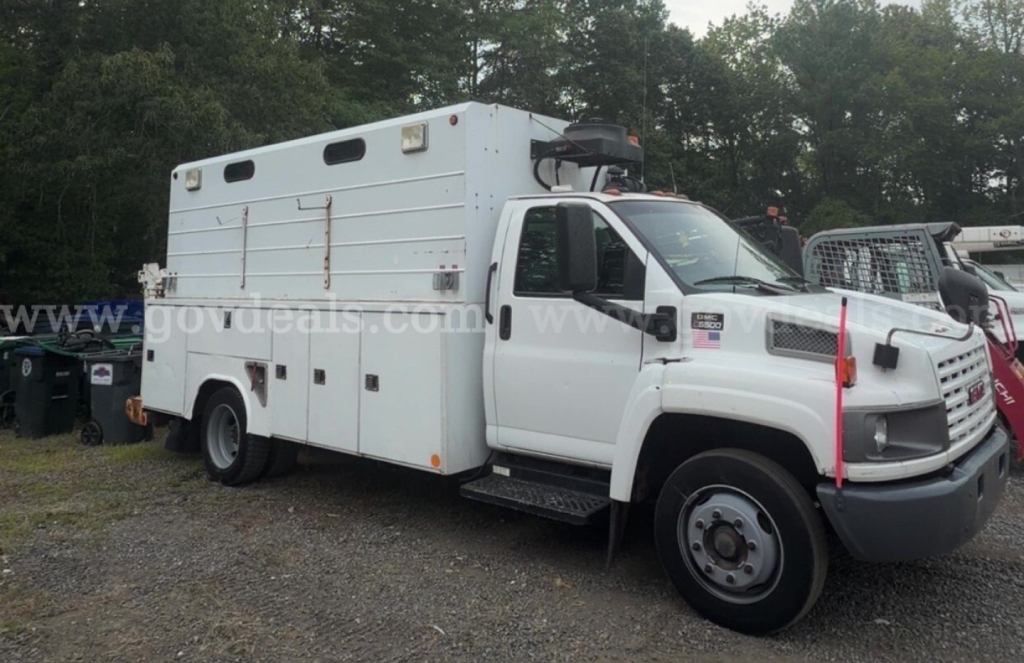 GMC truck utility/service body with enclosed utility compartments and ladder rack, side view showing cargo box and front cab.