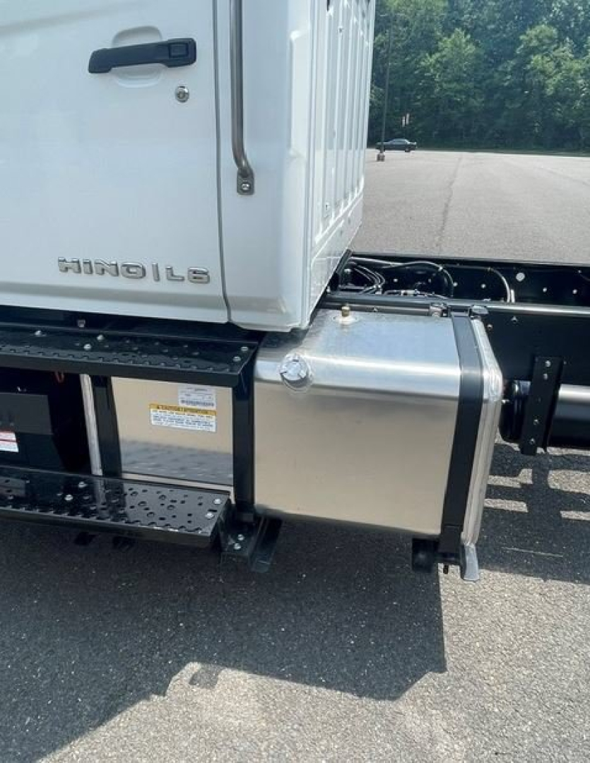 Hino L6 cab and chassis area showing side step, fuel/anti-exposure box, and truck lettering HINO L6 on cab side.
