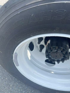 Truck wheel close-up showing tire with rim and valve, no explicit text readable aside from partial tire markings 'AHS' and tire model on sidewall.