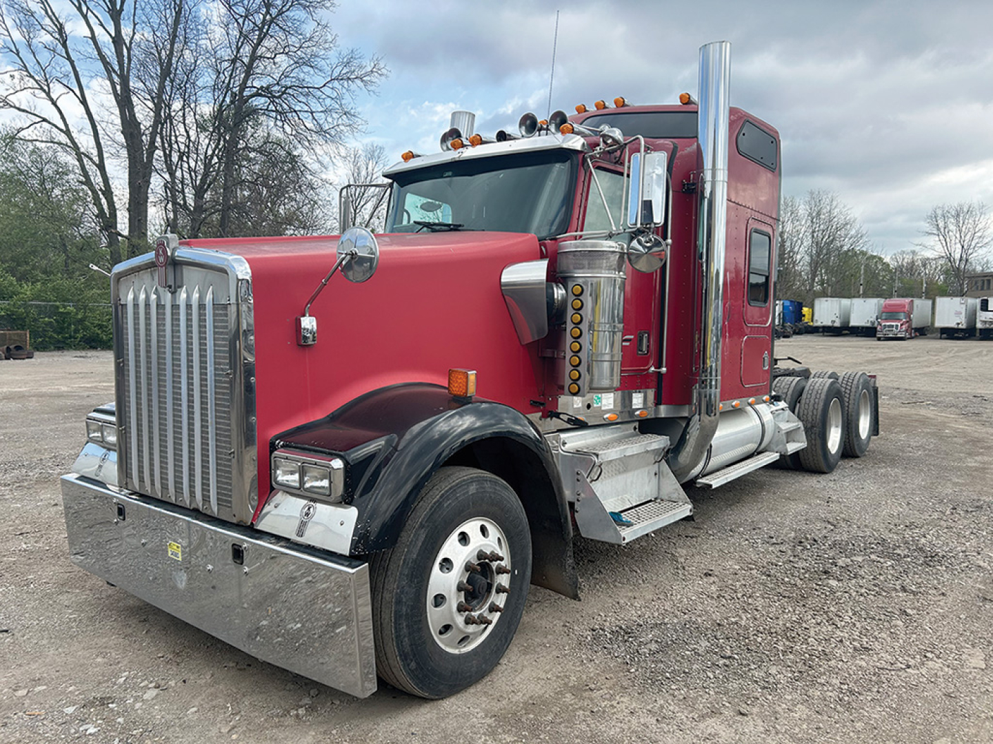 Kenworth W900L AeroCab sleeper tractor in red with chrome fuel tanks and steps, front grille, dual rear wheels, and tall exhaust stacks visible.