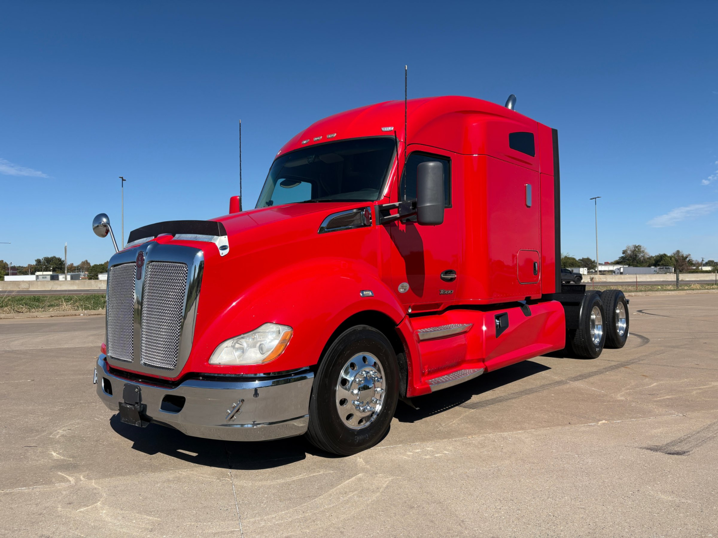 Kenworth T680 conventional sleeper truck in red, 2022 model year, front three-quarter view showing chrome bumper, large grille, dual rear axles, and side mirrors.