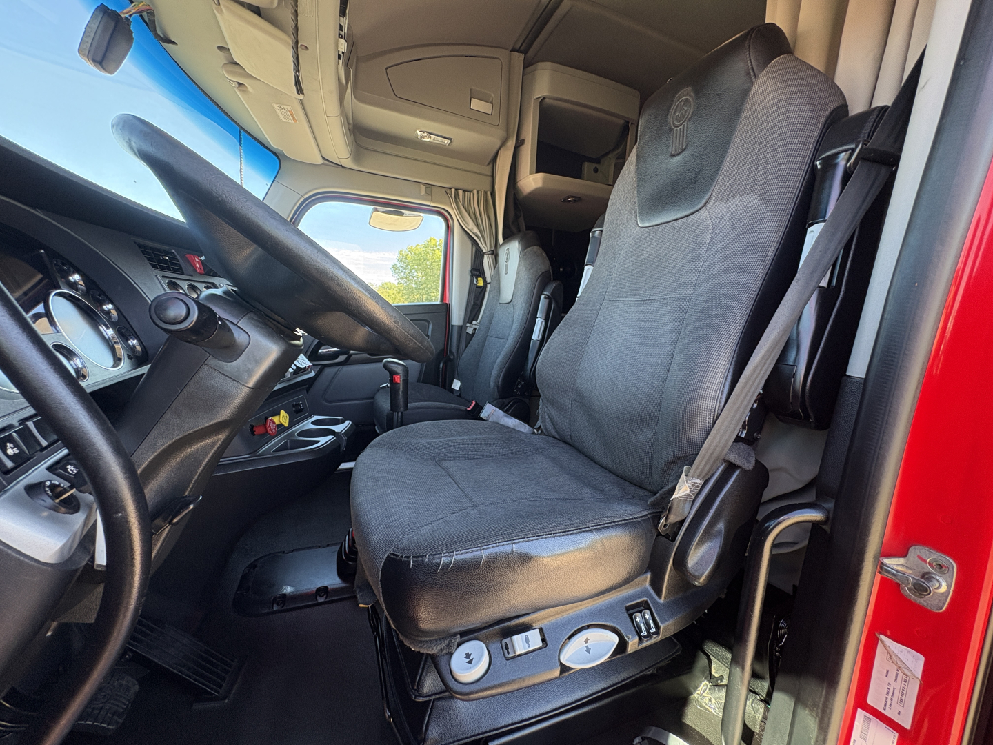 Truck cab interior of 2022 Kenworth T680 showing driver seat and dashboard with controls.