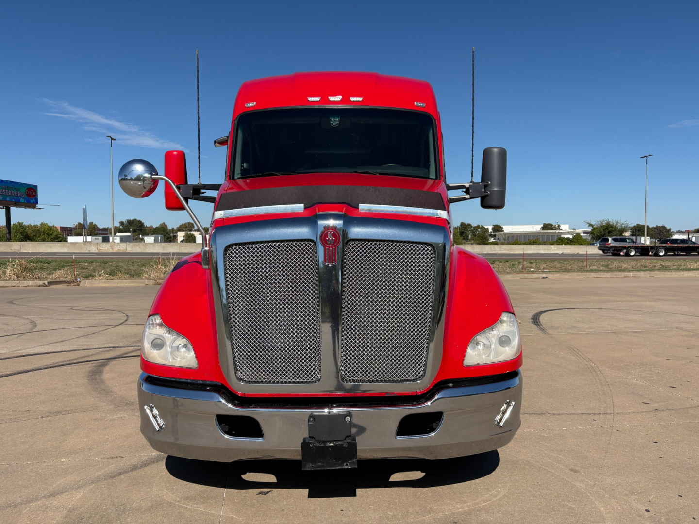 Kenworth T680 truck front view showing bold grille and headlights with red cab and chrome bumper