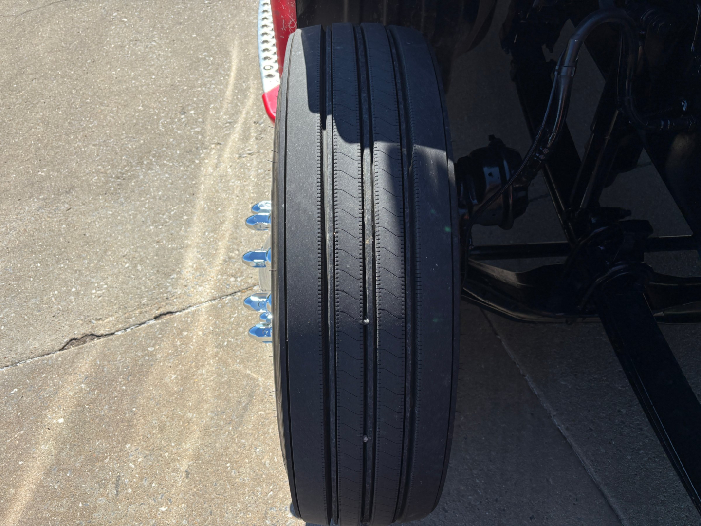 KW truck rear axle/view showing dual tire and air lines with black wheel and suspension components.