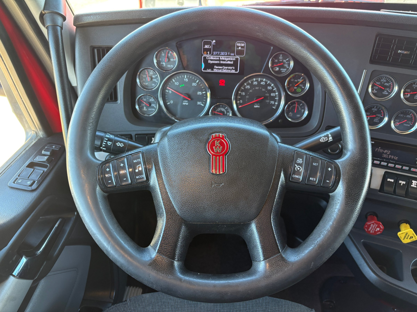 Kenworth T680 steering wheel and dashboard with multiple gauges visible including speedometer, tachometer, and control stalks.