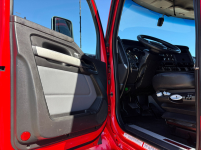 Kenworth T680 cab interior entering from open door showing driver seat steering wheel dashboard and door panel.