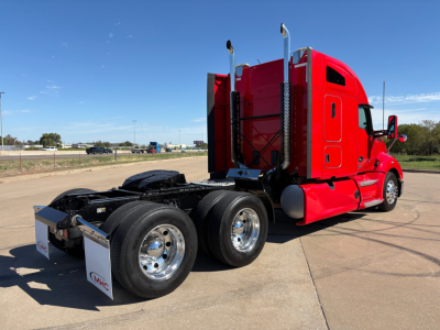 Kenworth T680 tractor sleeper cab in red, rear view showing dual rear axles and fifth wheel, no visible text on readable components.