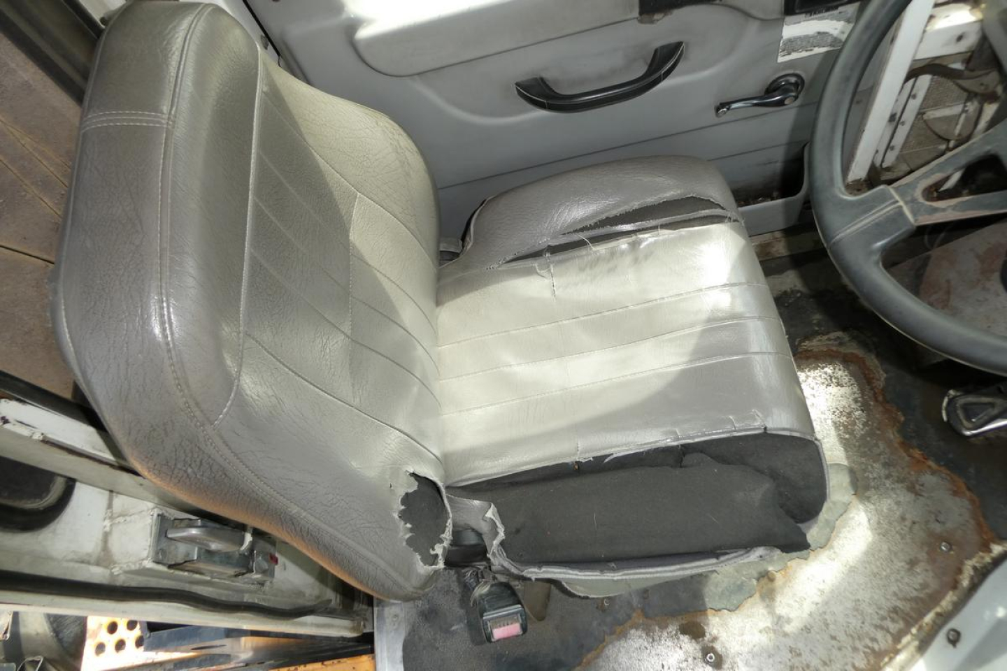 Seat and door area of a used Kalmar Ottawa YT50 truck showing a torn driver's seat with visible foam and wear.