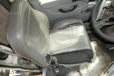 Seat and door area of a used Kalmar Ottawa YT50 truck showing a torn driver's seat with visible foam and wear.