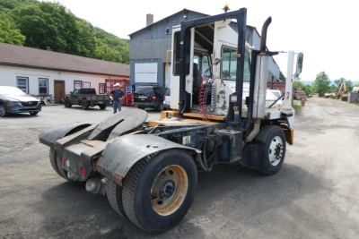Kalmar Ottawa YT50 yard truck viewed from rear-left, with cab raised and engine area visible; dual rear wheels, open wheel arches, and equipment lines in cab area.