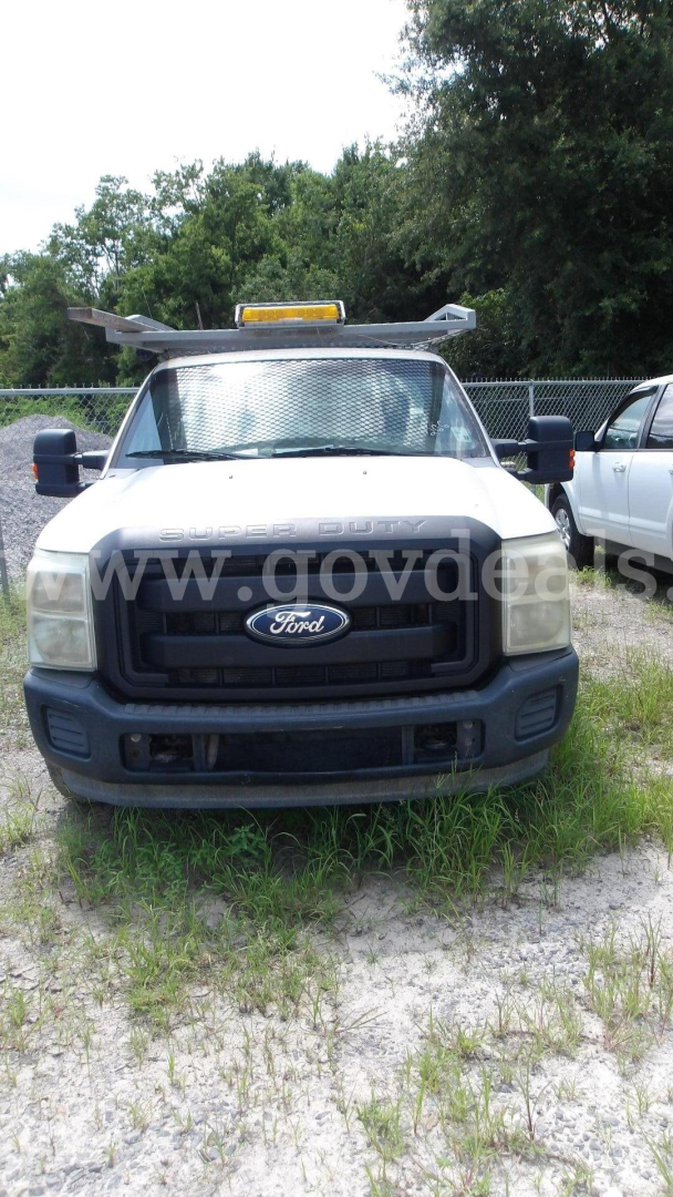 Ford F-250 utility truck front view showing grille with Ford emblem, yellow light bar on roof, protective mesh windshield screen, and side mirrors.