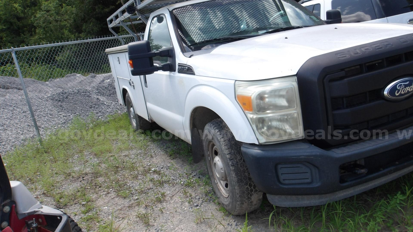 Ford F-250 utility/service truck front-right view showing white cab, black grille, and side mirror; VIN 1FTBF2A6ABEC78377 sticker not visible.