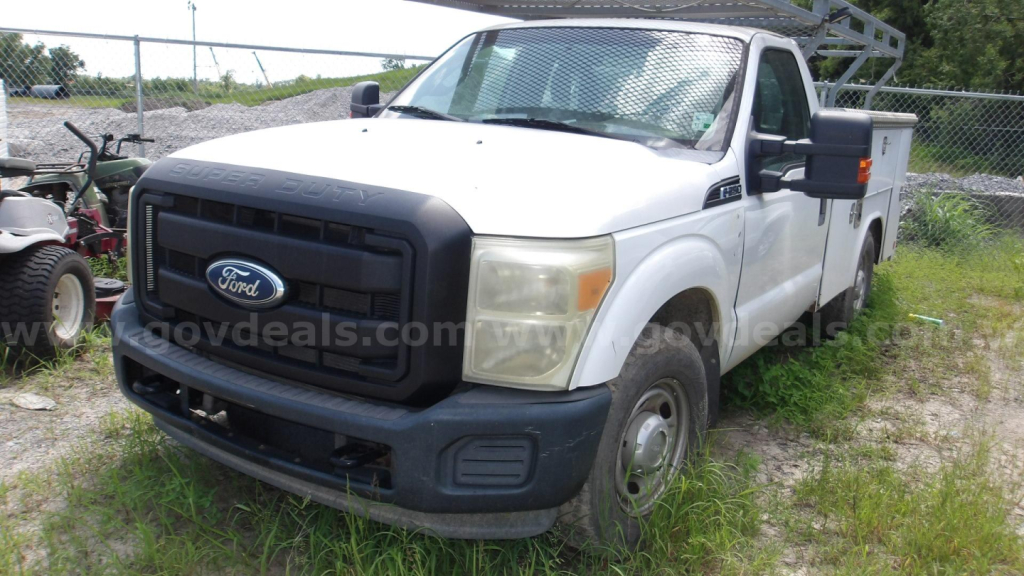 Ford F-250 utility truck in a used lot showing front grille, headlights, and side service bed.