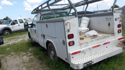 Service utility truck bed of a 2011 Ford F-250 with cargo platform and storage compartments, rear bumper and ladder rack visible, tail lights and bumper details.