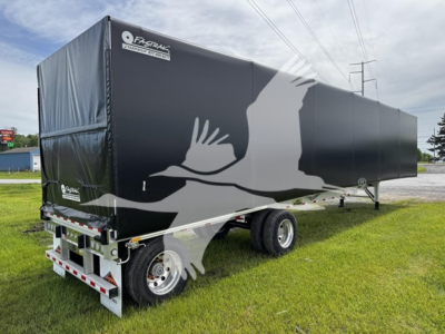 Curtainside trailer showing black fabric with white crane silhouette and rear underride guard. Side view reveals dual rear wheels, front hitch, and reflective markings.