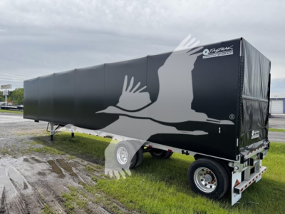 Curtainside trailer showing large white stork graphic on black cover with front cab-end and dual-axle undercarriage.