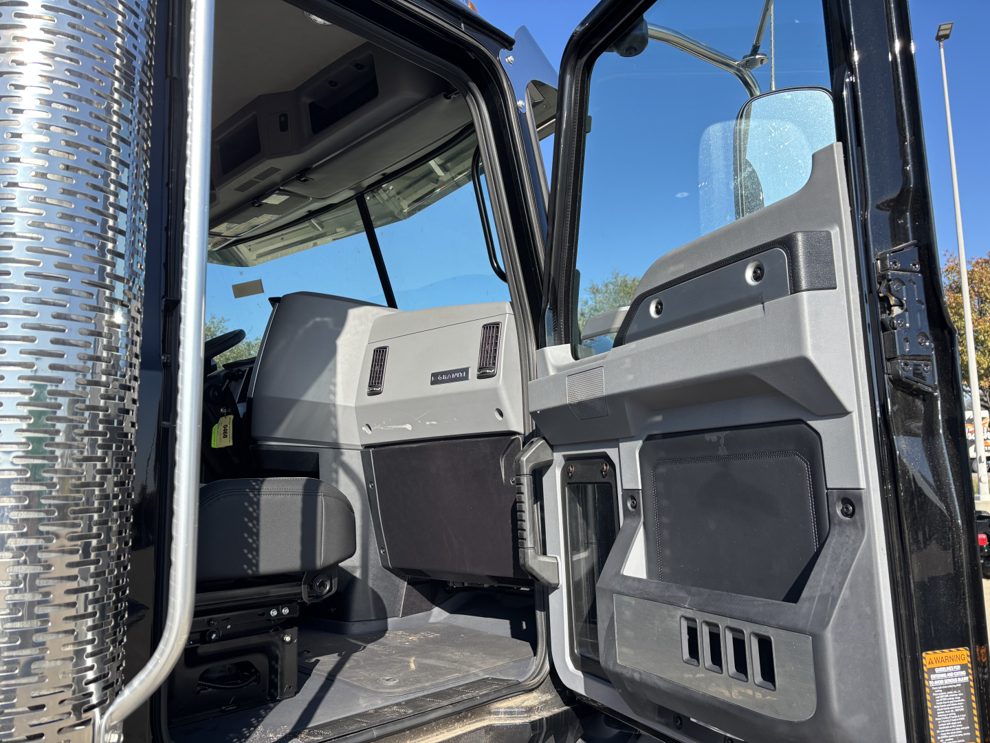 Cab interior of a 2025 Mack GR64B showing driver-side door, dashboard, and seating area with textured panels and vents.