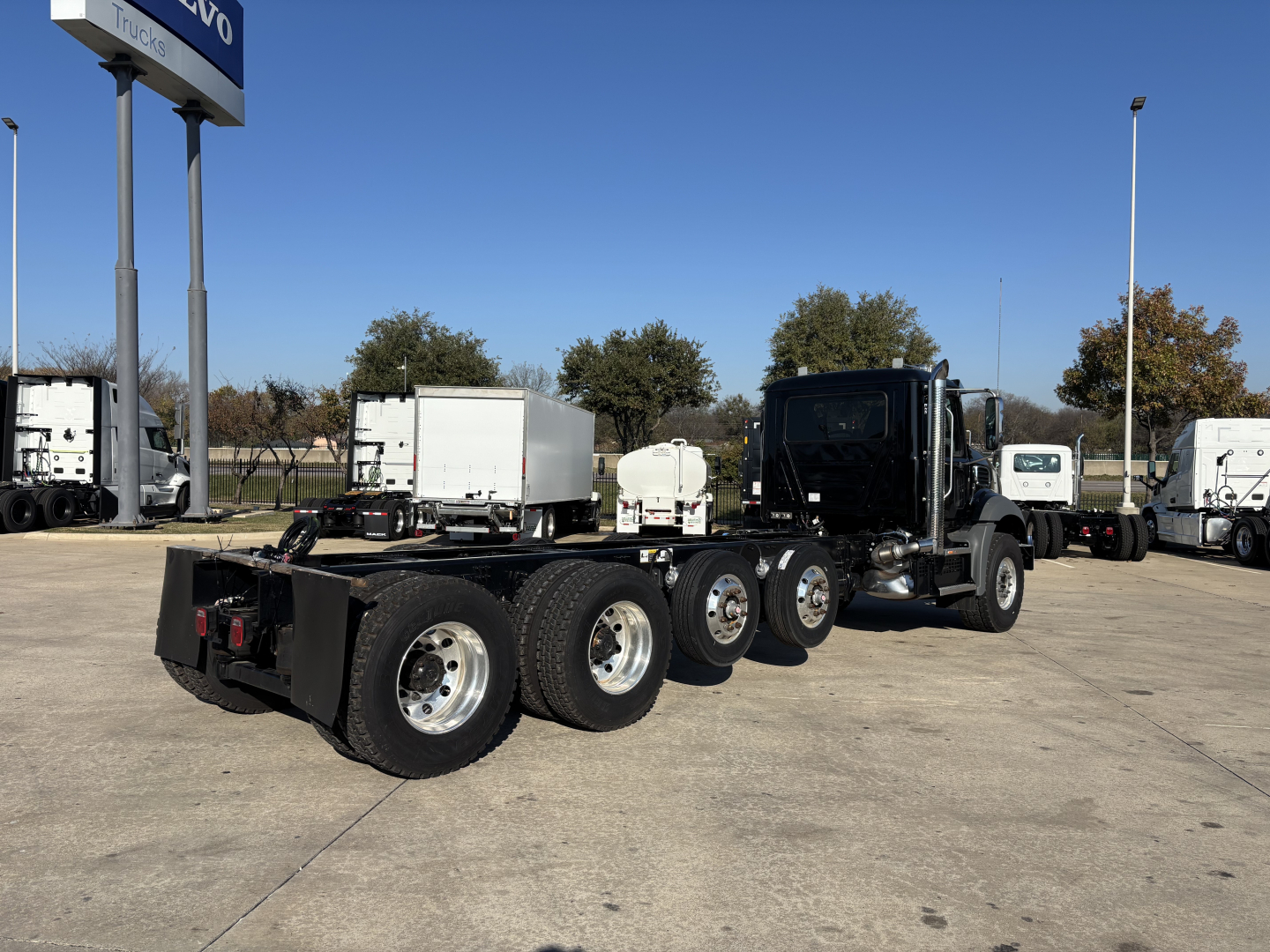 Mack GR64B cab and chassis truck with multiple axles and a black cab, rear view showing dual rear tandem axles and chrome wheels.